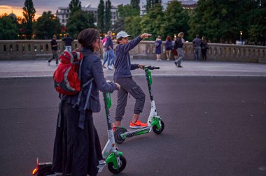 Berlin, Almanya - 3 Ağustos 2019: Berlin 'in merkezinde elektrikli scooterlarla seyahat eden turistler eski kentin tarihi arkaplanına karşı.