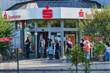 Berlin, Almanya - 17 Eylül 2020: Bazıları Covid-19 yüzünden yüz maskesi takan bir banka şubesinin önünde kuyruğa giren müşteriler.