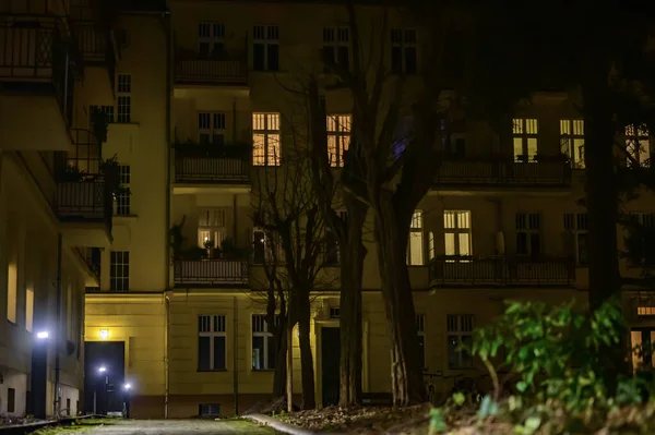 Berlin, Almanya 'da geceleri aydınlık bir yol boyunca uzanan bir yerleşim tesisinin arka binasının görüntüsü.