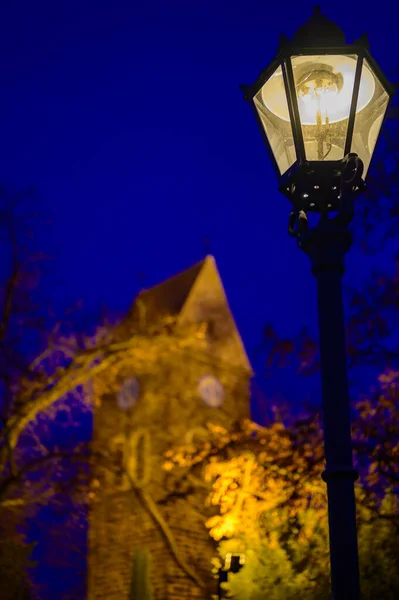 在右边你可以看到一个历史性的灯笼 在没有聚焦的背景下 矗立着一座历史性的村庄教堂 灯火通明 而在柏林 利什滕拉德 蓝色的时刻 — 图库照片