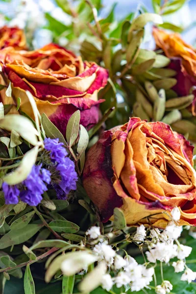 Close-up of a bouquet of dried roses and various complementary plants. Focussed is the rose on the right side.