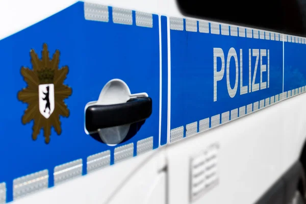Polizei という言葉と前景の腕のぼやけたベルリンの都市のコートを持つベルリンの警察の車の側面の詳細ビュー — ストック写真