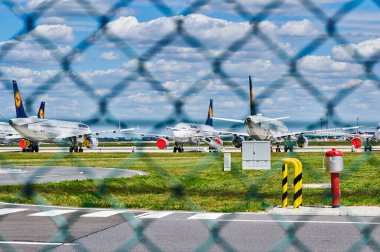 Berlin-Schoenefeld, Almanya - 20 Mayıs 2020: Corona salgınından dolayı ihtiyaç duyulmayan Berlin-Schoenefeld Havaalanı 'ndaki park halindeki uçaklar için zincirli tel örgülerden bakın.