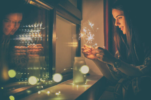 молодая женщина, которая зажигает фейерверки дома
