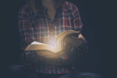 Genç bir kadın İncil karanlık bir odada kızlarla