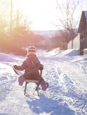 Küçük kız kırsal eski bir atlı kızak ile eğleniyor