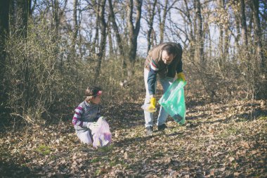 Baba ve kız parkta çöp toplama