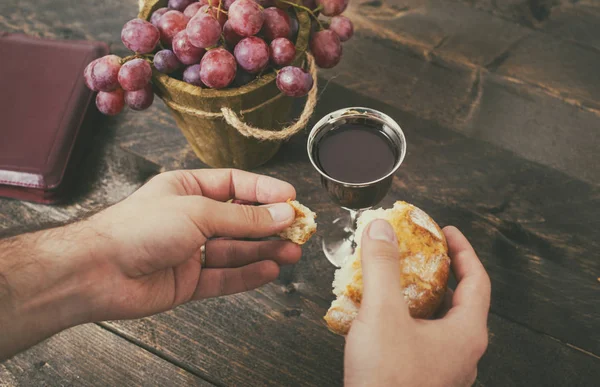 Mann beim Brotbrechen, mit Wein, Trauben und Bibel im Hintergrund — Stockfoto