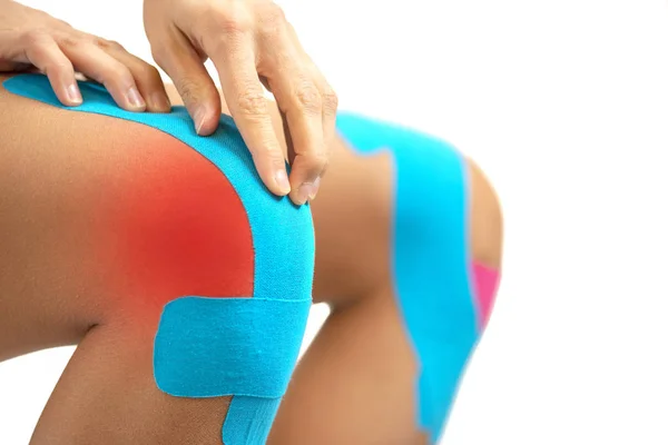 Mulher aplicando fita cinesio azul no joelho lesão — Fotografia de Stock