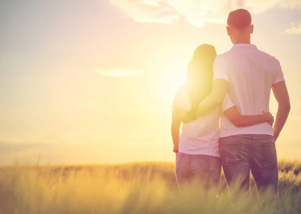 愛情深い若いカップルのバックビューは 密接に立って 自然を賞賛し 距離に何かを見て 夕日を楽しむ 脇にコピースペース — ストック写真