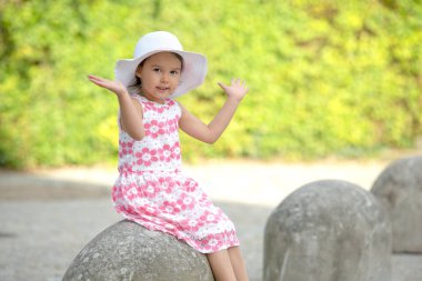 Sevimli küçük kız sıcak ve güneşli yaz gününde merdivenlerde oturan beyaz şapka