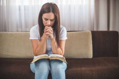 Genç kadın evde Tanrı ile kutsal bir ilişki içinde dua ediyor.