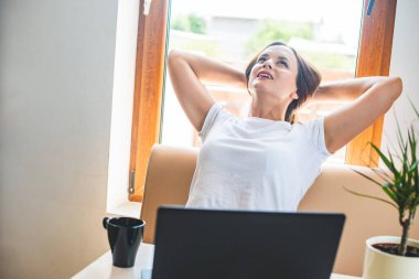 Sakin gülümseyen kadın ellerini başının arkasına koyuyor, mutlu kadın işten sonra dinleniyor, gözleri kapalı eğleniyor, stres yok.