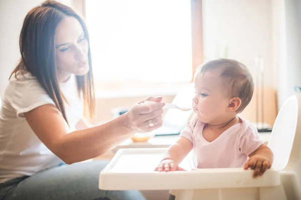 母は娘にスプーンで食べさせる — ストック写真