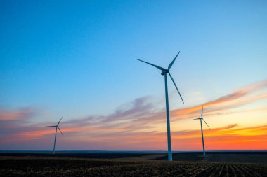 Günbatımında elektrik üretimi için yel değirmenleri