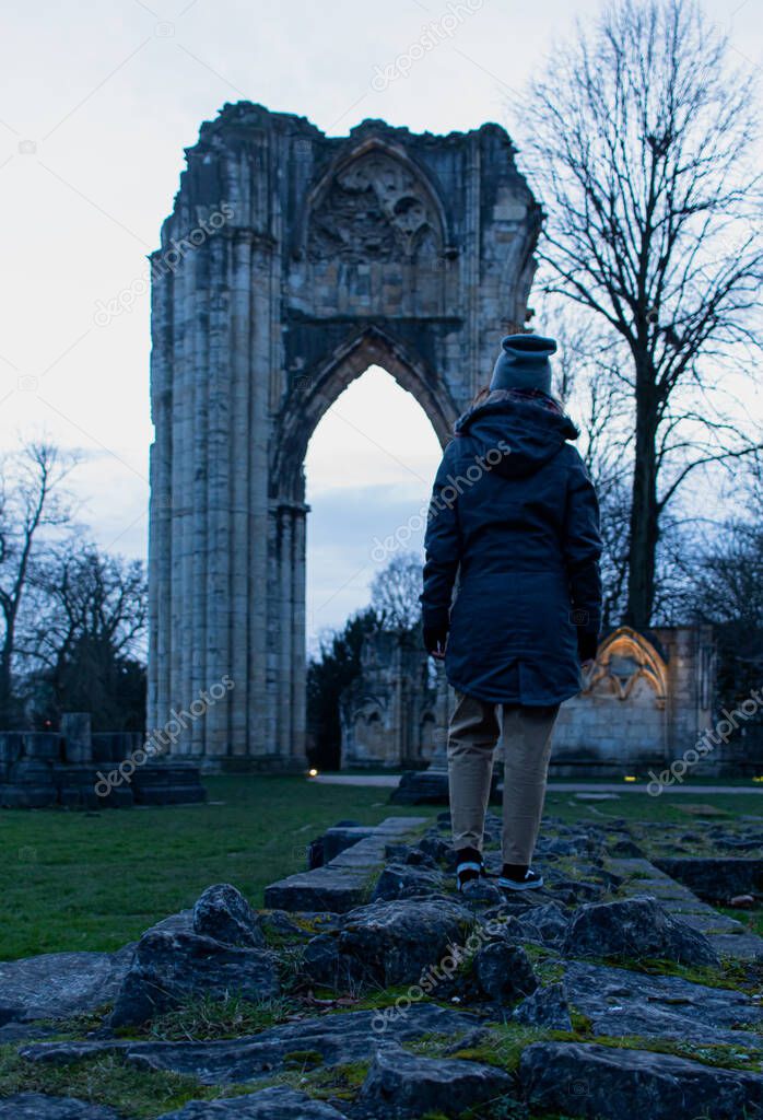 Attractive young female visiting St. Marys Abbey Ruins situated in Museum Gardens in York, England