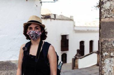 Coronavirus salgını sırasında yüz maskesi takmış yaşlı bir kasabayı ziyaret eden çekici genç bir kadın.