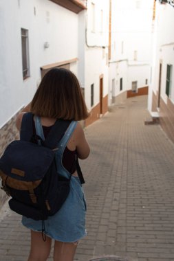 Çekici genç bir kadın, İspanya 'nın Cadiz kentindeki bir köyün beyaz sokaklarında yürürken refleks kamerasıyla fotoğraf çekiyor.