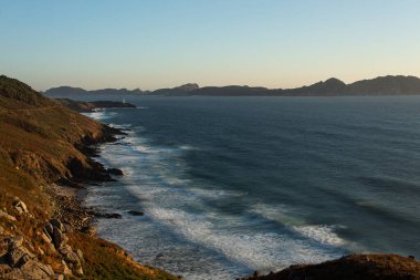 Gün batımında kıyıya ulaştıklarında, arka planda ünlü Galiçya adaları olan dalgaların kırılma görüntüsü