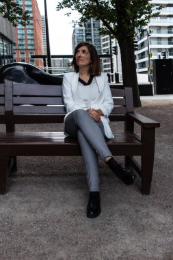 Beyaz takım elbiseli çekici genç bir kadın bankta oturup İngiltere 'deki ofisinde toplantıya başlamak için bekliyor.