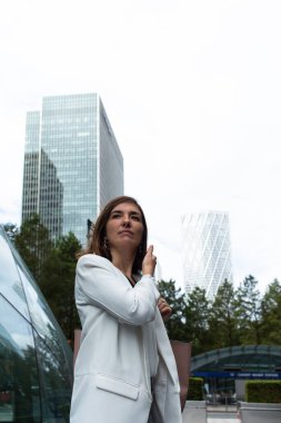 Beyaz takım elbiseli çekici genç bir kadın Londra, İngiltere 'deki ofisinde bir toplantıya başlamak için mali alanda bekliyor.