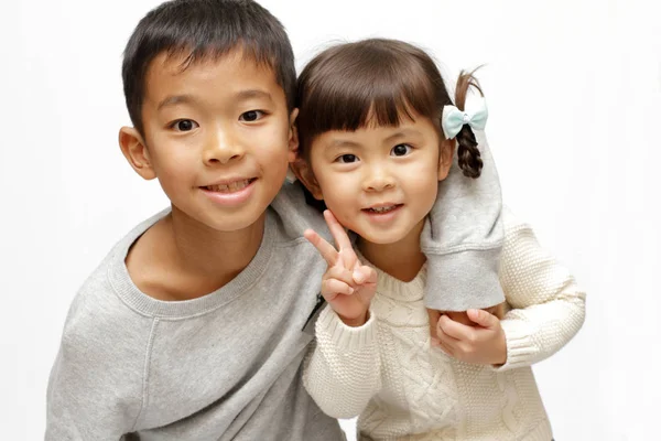 Japonés hermano y hermana poniendo brazos alrededor de la otra sholders (9 años de edad, niño y 4 años de edad, niña ) —  Fotos de Stock