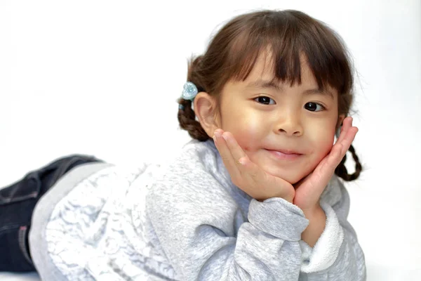 Liggande japansk flicka med att vila hakan i händer (4 år gammal) — Stockfoto
