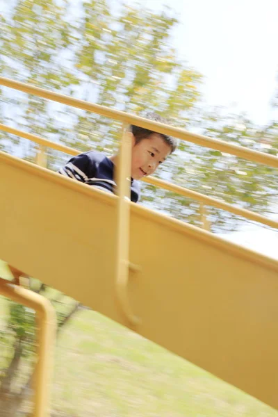 Japanese boy on the slide (fourth grade at elementary school) — Stock Photo, Image