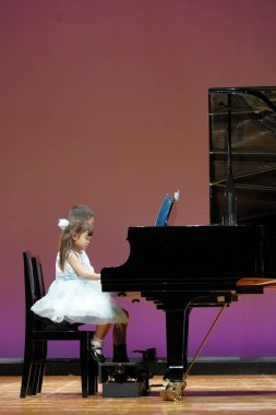 Japon kardeşi ve kız kardeşi sahnede piyano oynarken (9 yaşında çocuk ve 4 yaşında kız)