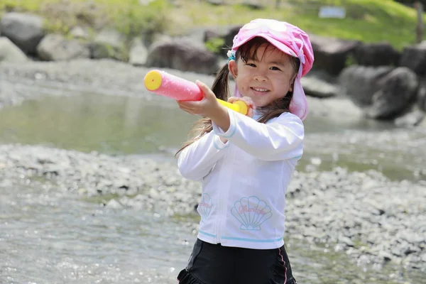 Ragazza giapponese che gioca nel fiume con pistola ad acqua (4 anni ) — Foto Stock