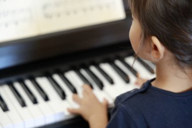 Japanese girl playing a piano (4 years old) clipart