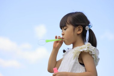 Japon kız mavi gökyüzünün altında baloncukla oynuyor (5 yaşında))