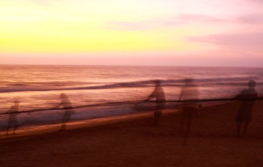 Bulanık balıkçıların hayalet siluetleri gün batımında Sri Lanka sahillerinde ağlarını yakalıyor.