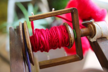 Eski ahşap dönen tekerlekten kırmızı çiğ merino yünü ile broşürü kapat.