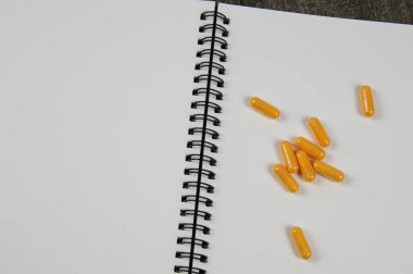 Metin için kopyalama alanı olan tıbbi konular için arkaplan: Beyaz boş sayfalar ve sarı haplar grubundan oluşan açık halka dosyasına bak