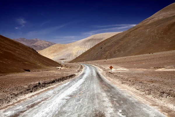 在智利阿塔卡马沙漠 蜿蜒的土路通向干旱的山谷 有着贫瘠的黄褐色山丘 — 图库照片