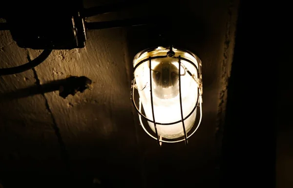 暗い地下室の天井から輝くグリッドと古い隔離された防湿照明器具の閉鎖 — ストック写真
