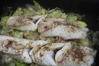 Balık yemeğinin hazırlanması: soğan, kimyon, sarımsak ve biberle tatlandırılmış haşlanmış taze morina filetosu ile izole edilmiş fırın tepsisine bakın.