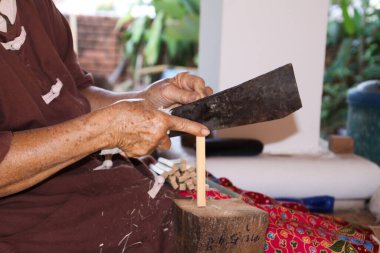 Chiang Mai, Tayland 'da kağıt şemsiye fabrikasında bambu ağacını bıçakla kıran bir kadın.