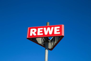 Heinsberg, Almanya - 23 Mart. 2020: Açık mavi gökyüzüne karşı Alman Rewe süpermarket zincirinin izole işaretini kapat