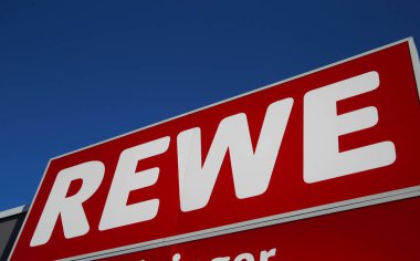 Heinsberg, Almanya - 23 Mart. 2020: Açık mavi gökyüzüne karşı Alman Rewe süpermarket zincirinin izole işaretini kapat