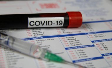 Viersen, Almanya - 22 Mart. 2020: Yalıtılmış kan örneği tüpünü covid-19 ve şırınga ile kapatın. Bulanık laboratuvar test isteği formu arka planı.