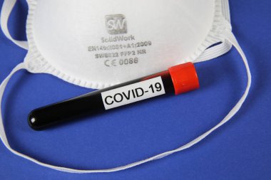 Viersen, Almanya - 28 Mart 2020: İzole CE sertifikalı ffp2 maskeli kan örneği tüp covid-19, mavi arkaplan