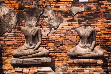 Ayutthaya, Tayland 'da kırmızı tuğlalı bir duvarın önündeki izole kadim başsız büstlere bakın.