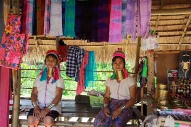 LONGNECK KAREN VILLAGE, THAILAND - 17 ARALIK. 2017: Bambu kulübesinin önünde oturan iki uzun boyunlu kadın