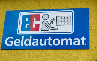 Sarı duvardaki izole edilmiş mavi levhada ATM 'yi göster (Almanca 