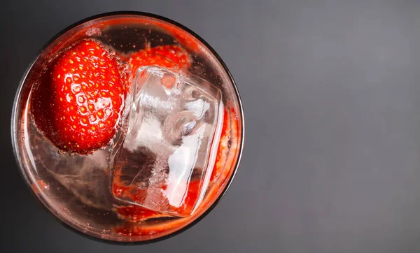 顶部俯瞰孤立的鸡尾酒杯与红色草莓 闪耀的滋养水和冰块 重点放在冰块右边 — 图库照片