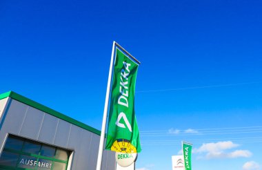 Dinslaken, Almanya - 18 Aralık. 2019: Bulutsuz mavi gökyüzüne karşı Alman denetçi firması Dekra 'nın logosu ve harfleriyle yeşil bayrak