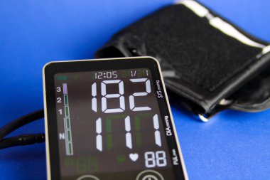 Yüksek diyastolik ve sistolik kan basıncını gösteren manşetlerle dijital sfenometre monitörünü kapat