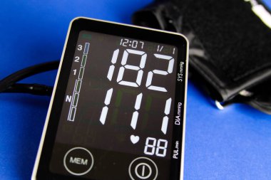 Yüksek diyastolik ve sistolik kan basıncını gösteren manşetlerle dijital sfenometre monitörünü kapat